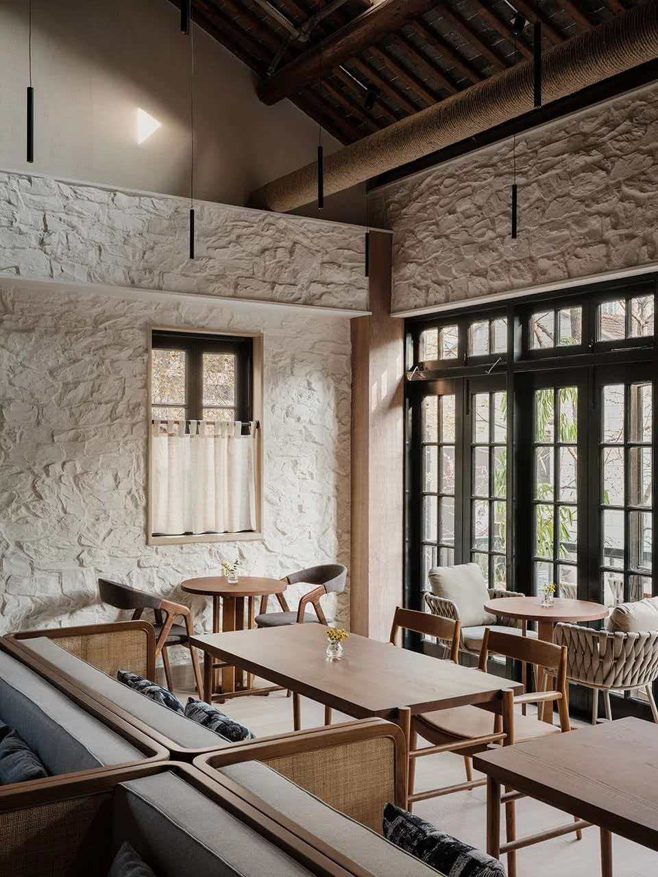 Airy restaurant with white rough stone walls and dark timber roof beams